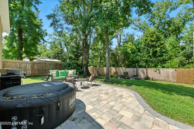 a view of a backyard with table and chairs under an umbrella with wooden fence
