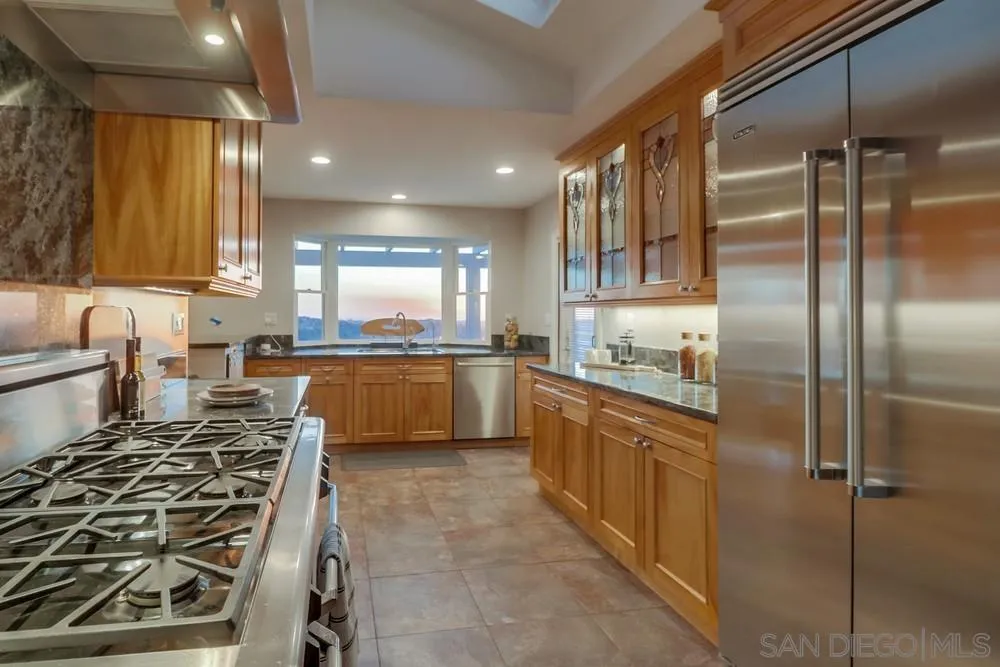 7970 Pasadena Avenue La Mesa, CA 91941 - Photo 10 of 38 a kitchen with stainless steel appliances granite countertop a refrigerator a sink and white cabinets