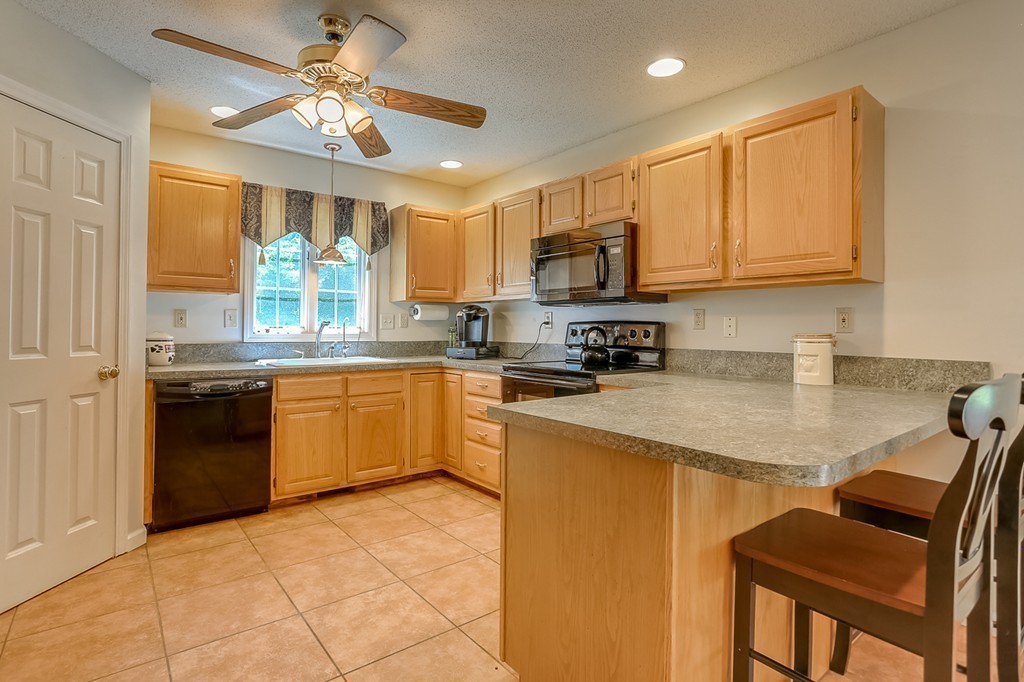 47 Babcock Tavern Road Ware, MA 01082 - Photo 5 of 27 a kitchen with stainless steel appliances granite countertop a sink a stove a refrigerator a microwave oven with a dining table and chairs