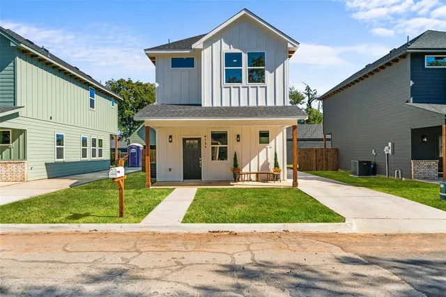a view of a white house with a big yard and large tree