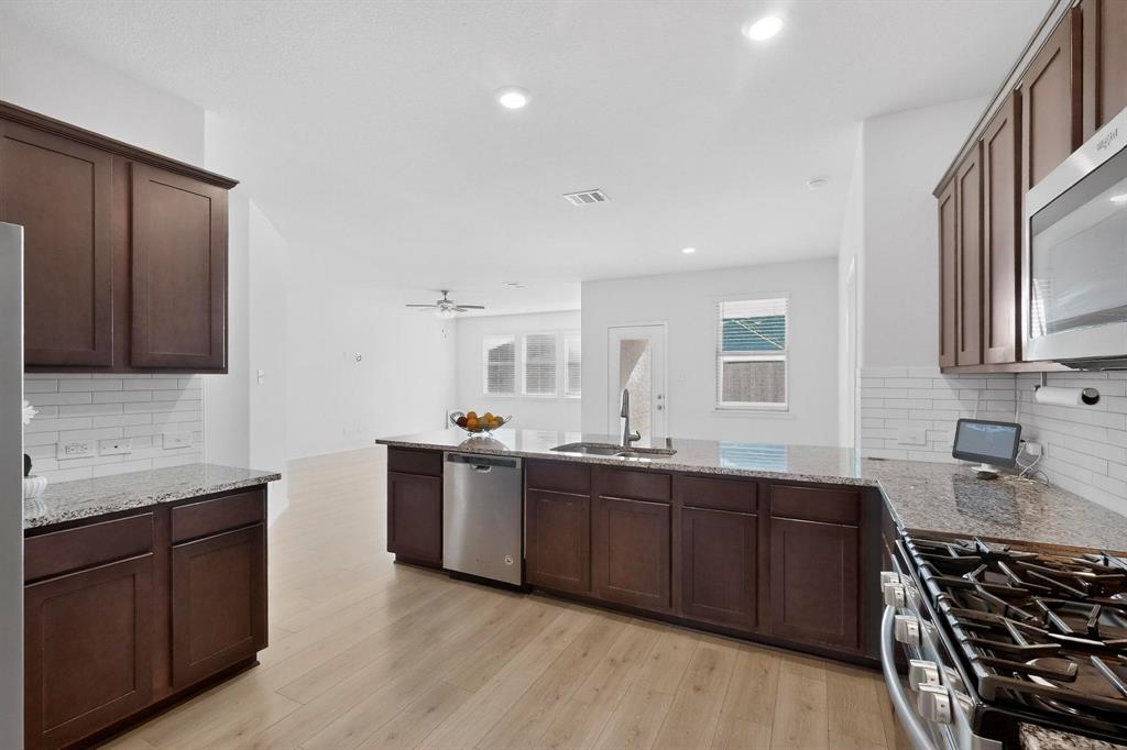 2917 Lampasas Lane Little Elm, TX 75068 - Photo 11 of 36 a kitchen with stainless steel appliances granite countertop wooden cabinets a sink and dishwasher