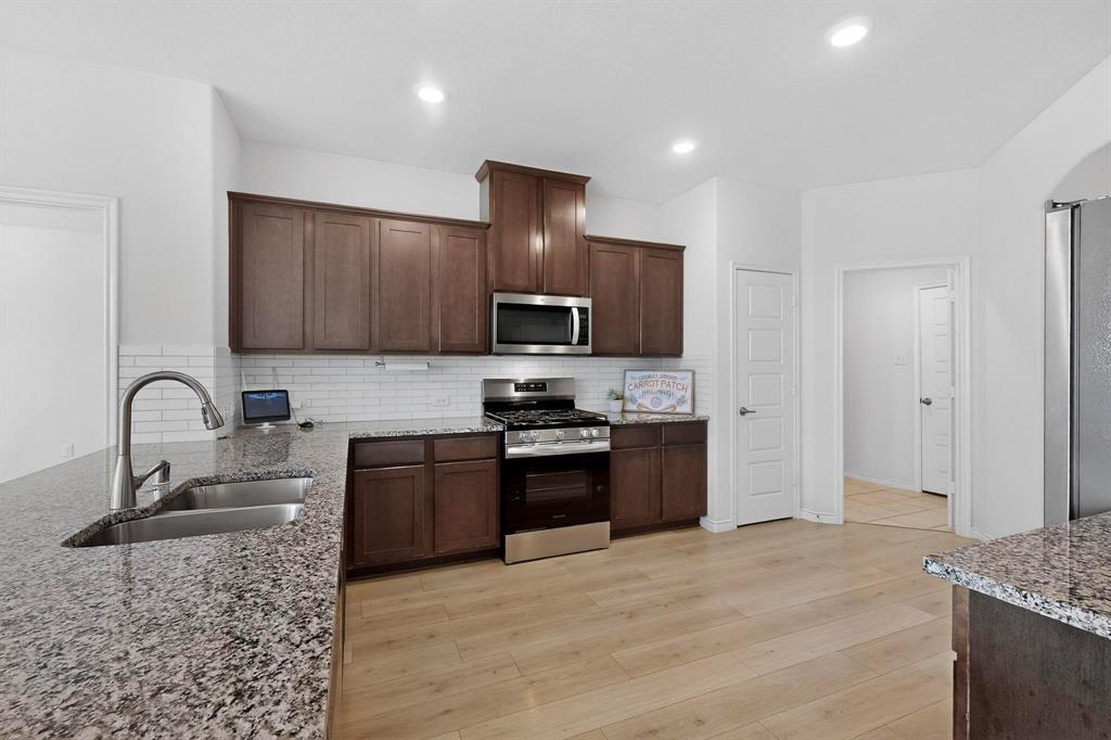2917 Lampasas Lane Little Elm, TX 75068 - Photo 12 of 36 a kitchen with stainless steel appliances granite countertop a sink stove and refrigerator