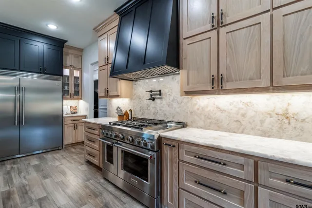 a kitchen with stainless steel appliances granite countertop a stove a refrigerator and a sink with wooden cabinets