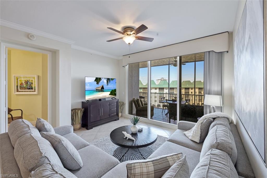 Living area with light tile patterned flooring, a ceiling fan, and ornamental molding