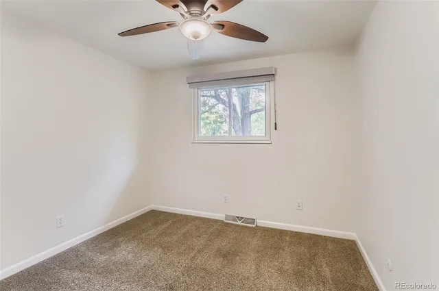 an empty room with a window and a fan