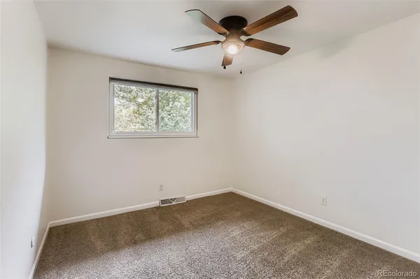 an empty room with a window and a fan