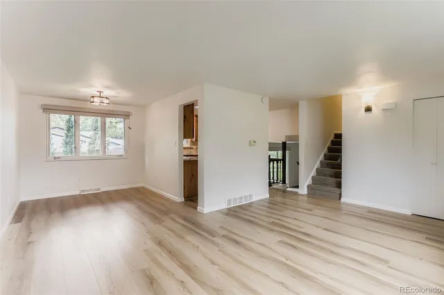 an empty room with wooden floor and stairs