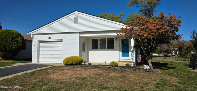 a view of a white house next to a yard and large trees
