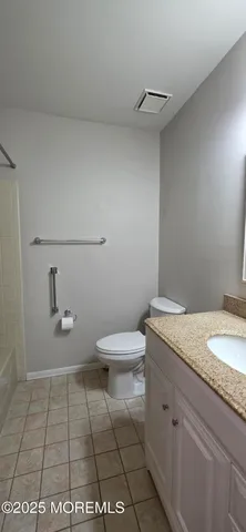 a bathroom with a granite countertop toilet and a sink