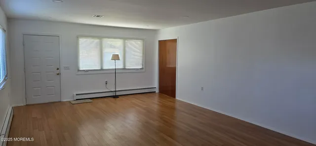 an empty room with wooden floor and window