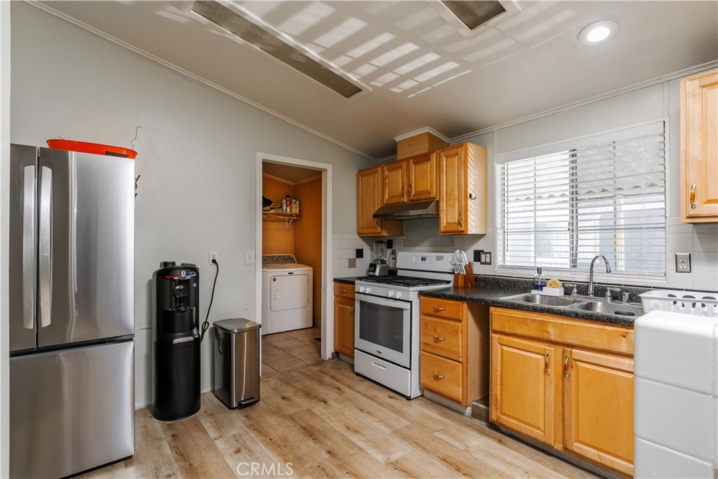 10350 Base Line Road, Unit 192 Rancho Cucamonga, CA 91701 - Photo 17 of 35 a kitchen with stainless steel appliances granite countertop a refrigerator a stove a sink dishwasher and a refrigerator with wooden floor