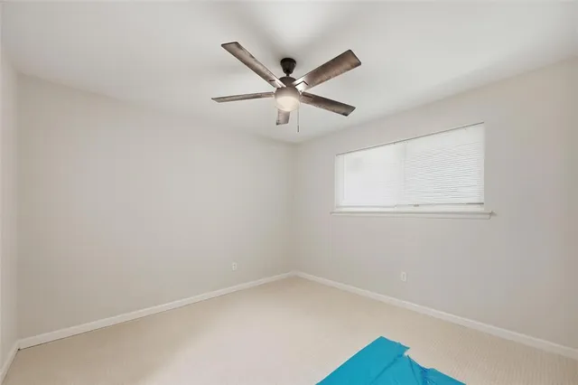 an empty room with a window and a ceiling fan