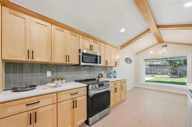 a kitchen with stainless steel appliances granite countertop a stove a sink and a microwave