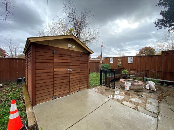 a backyard of a house with table and chairs and wooden fence