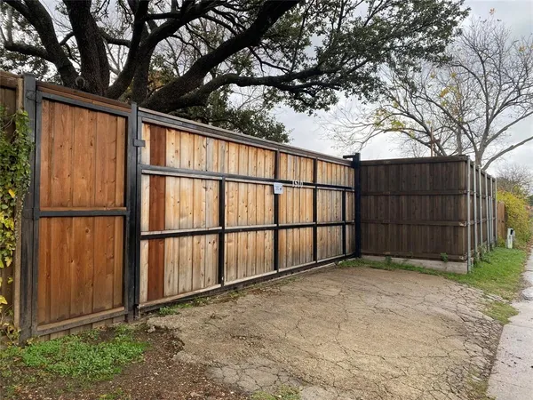 a view of backyard with large tree and wooden fence