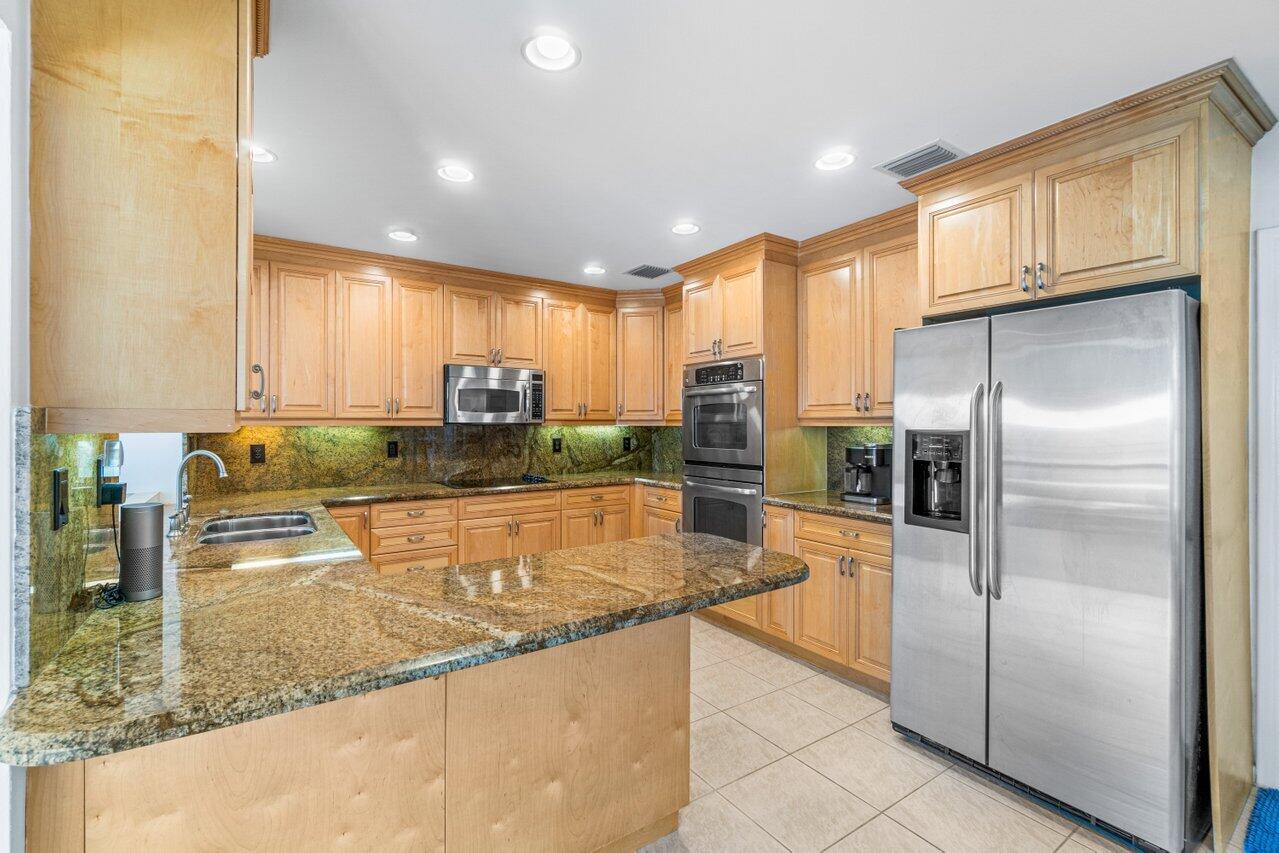 1350 Southwest 13th Place Boca Raton, FL 33486 - Photo 9 of 26 a kitchen with stainless steel appliances granite countertop a refrigerator a stove and a sink