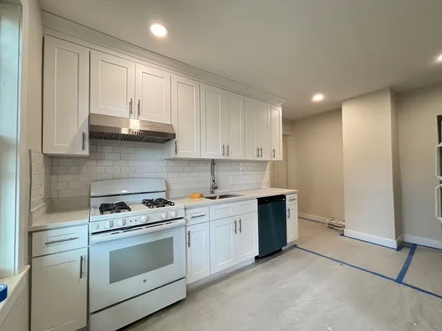 a kitchen with stainless steel appliances white cabinets and a stove top oven