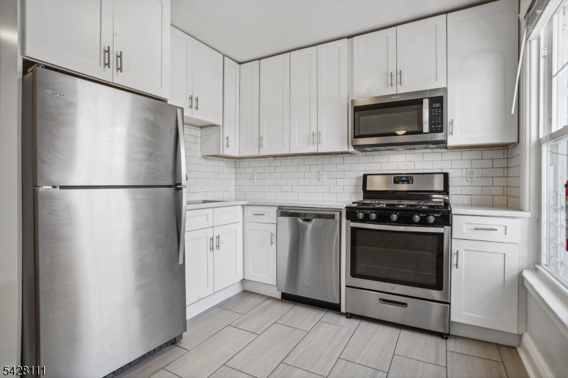 60 2nd Street South Orange, NJ 07079 - Photo 6 of 18 a kitchen with stainless steel appliances white cabinets white stove a microwave and a refrigerator
