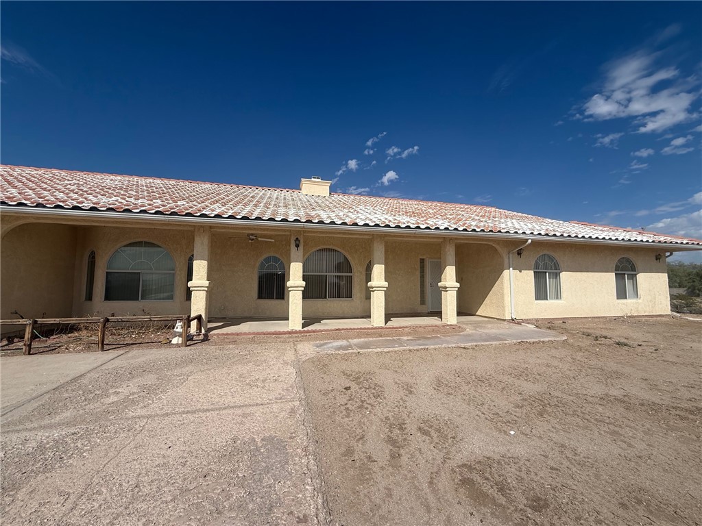 1845 Dunlap Road Fort Mohave, AZ 86426 - Photo 1 of 16 Back of house featuring stucco siding, a chimney, a tiled roof, and a porch