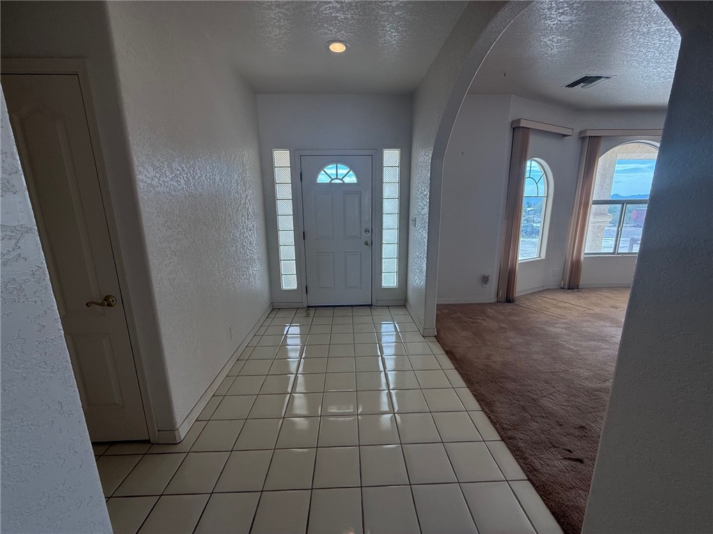 1845 Dunlap Road Fort Mohave, AZ 86426 - Photo 2 of 16 Entryway with a textured wall, a textured ceiling, light tile patterned floors, arched walkways, and healthy amount of natural light