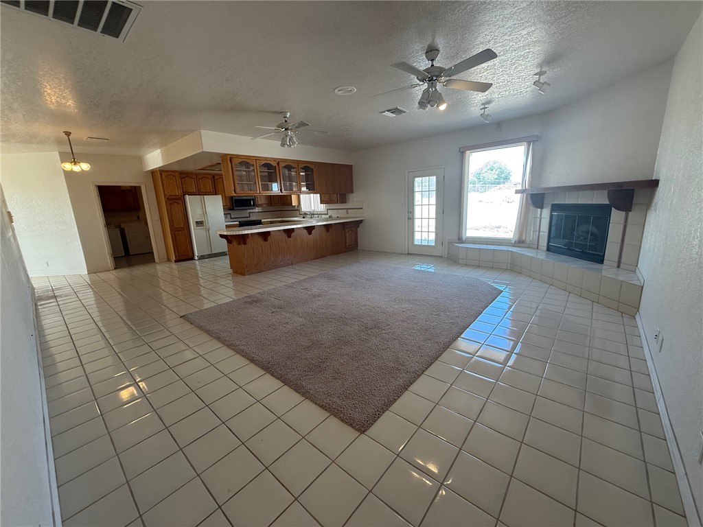 1845 Dunlap Road Fort Mohave, AZ 86426 - Photo 16 of 16 Kitchen with open floor plan, glass insert cabinets, a textured ceiling, brown cabinetry, and light countertops