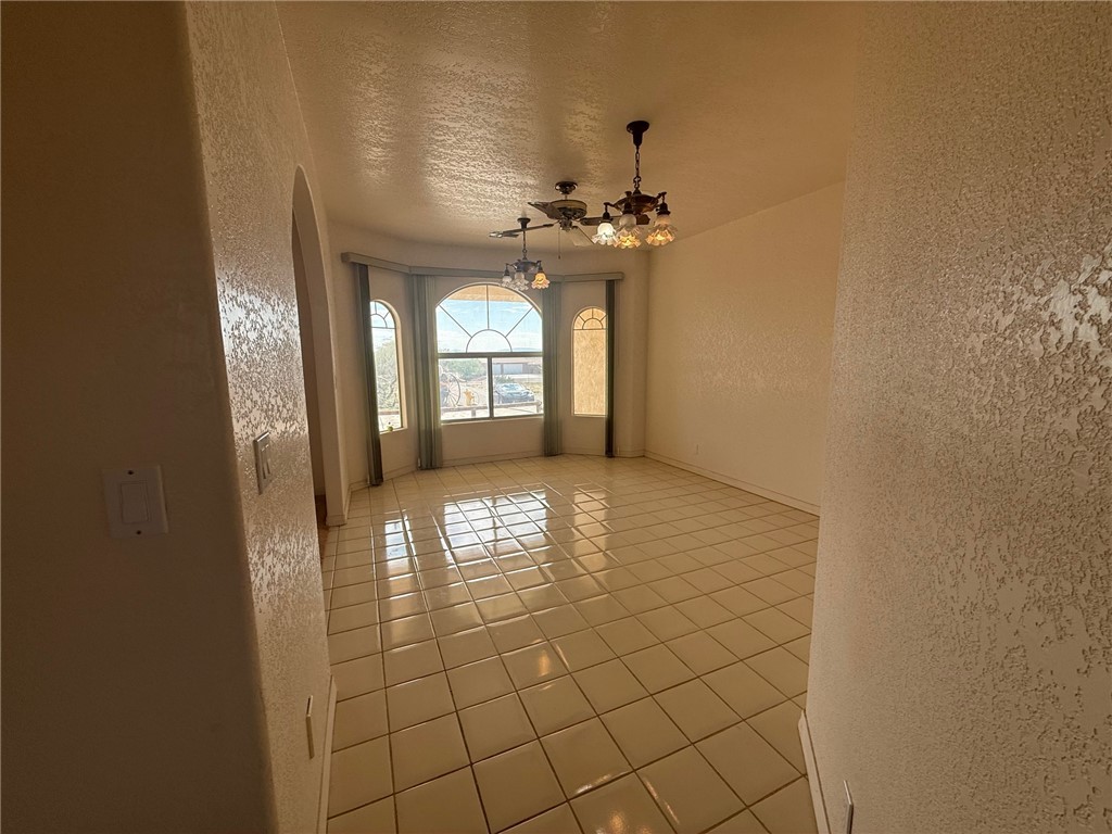 1845 Dunlap Road Fort Mohave, AZ 86426 - Photo 5 of 16 Spare room featuring a textured wall, a textured ceiling, light tile patterned floors, arched walkways, and a chandelier