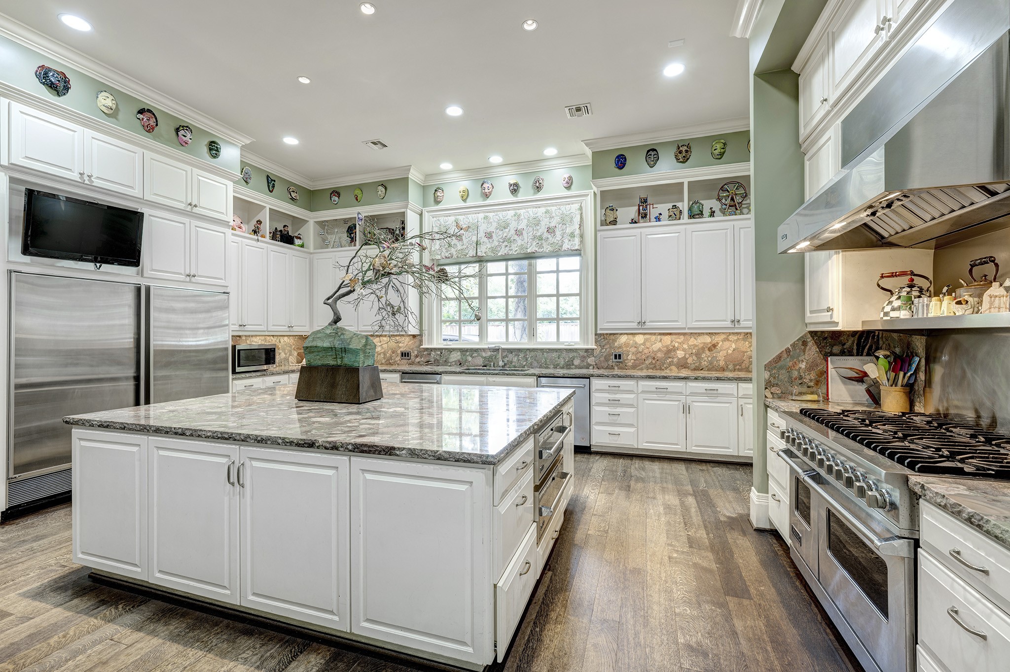 3653 Inverness Drive Houston, TX 77019 - Photo 14 of 39 One of the standout features of this kitchen is its extensive selection of professional appliances. It is equipped with an industrial range and a hood vent, complemented by elegant hardwood flooring and a granite countertop. The overall design offers plenty of usable space, making it perfect for entertaining guests.