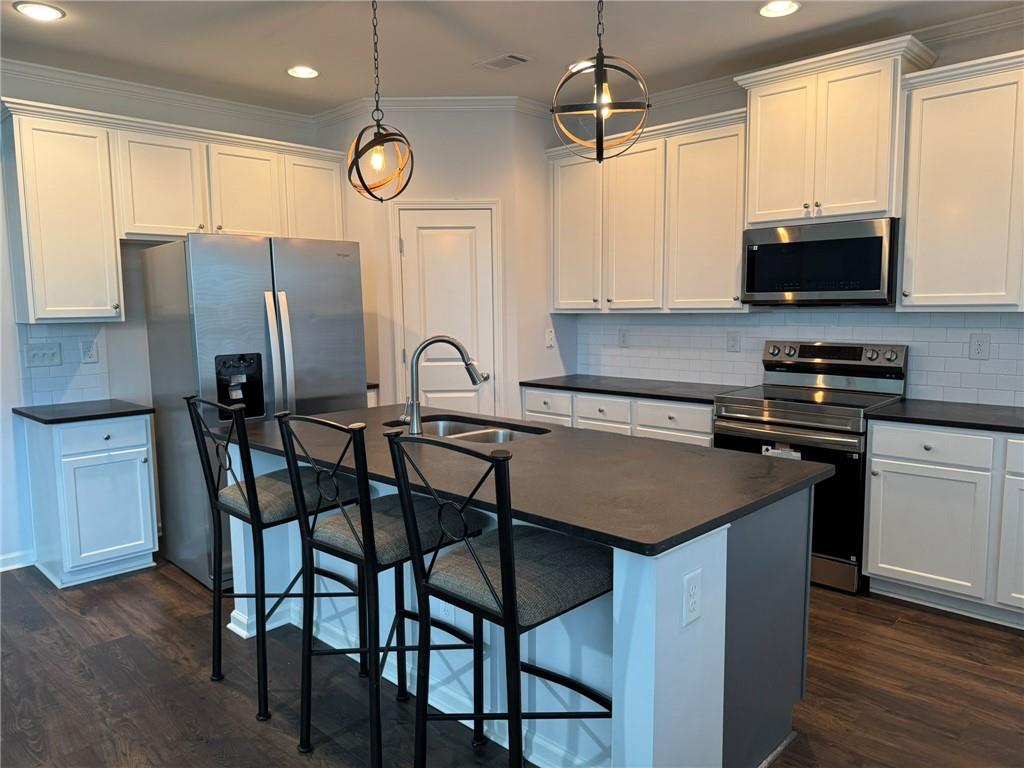 5414 Long Branch Way Flowery Branch, GA 30542 - Photo 12 of 37 a kitchen with stainless steel appliances granite countertop a stove a refrigerator a microwave a sink and a dining table with wooden floor