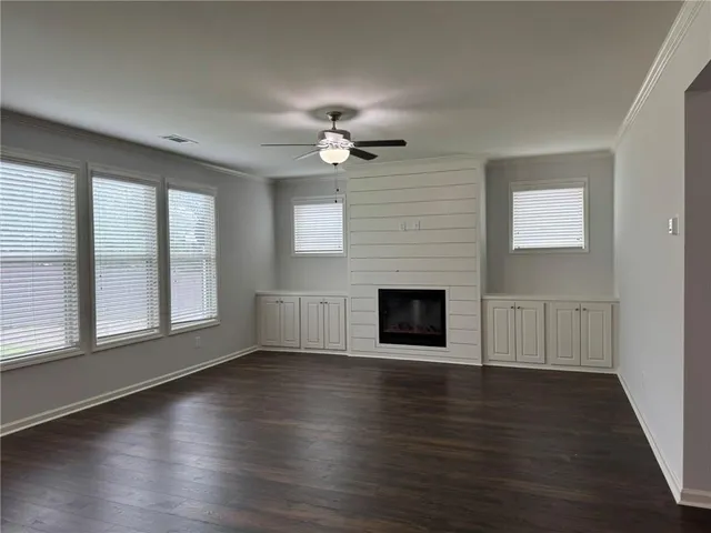 an empty room with wooden floor fireplace and windows