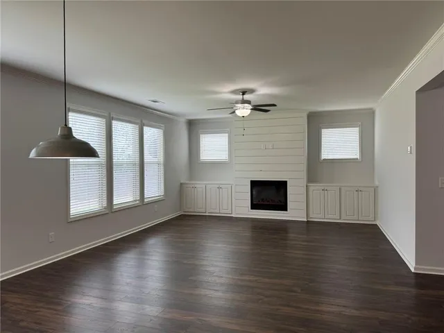 an empty room with wooden floor fireplace and windows