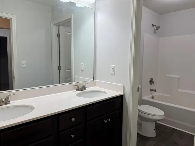 a bathroom with a granite countertop sink toilet a large mirror and bathtub