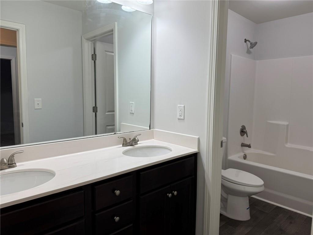 5414 Long Branch Way Flowery Branch, GA 30542 - Photo 21 of 37 a bathroom with a granite countertop sink toilet a large mirror and bathtub
