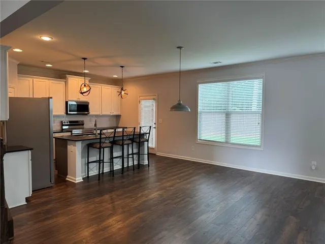 an open kitchen with wooden floor and stainless steel appliances