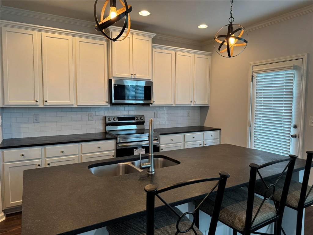 5414 Long Branch Way Flowery Branch, GA 30542 - Photo 10 of 37 a kitchen with a table chairs microwave and cabinets