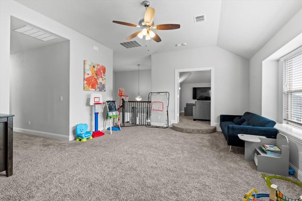 620 Shadow Trail Frisco, TX 75033 - Photo 22 of 36 Carpeted room featuring a vaulted ceiling with a ceiling fan, window with blinds, and a partial view to a lower-level room