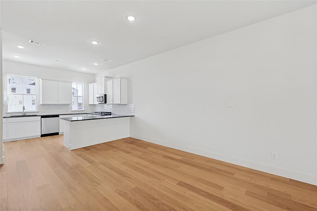 809 Concan Drive Plano, TX 75075 - Photo 7 of 40 Kitchen featuring white cabinets, light wood-type flooring, appliances with stainless steel finishes, and tasteful backsplash