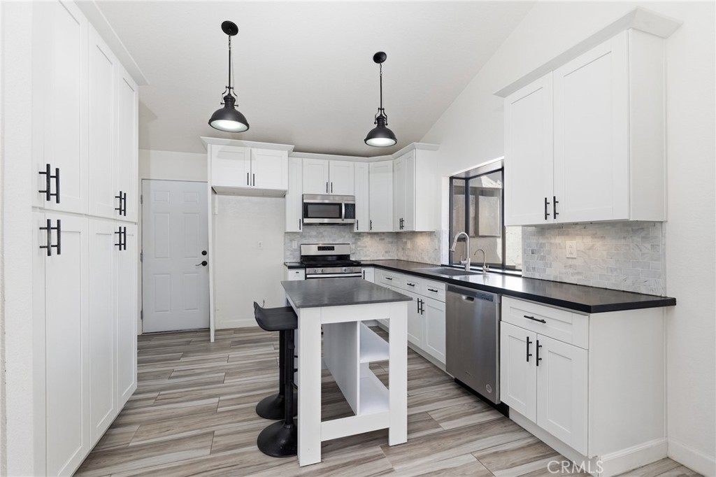 9841 Golden Arrow Lane Rancho Cucamonga, CA 91701 - Photo 11 of 53 a kitchen with stainless steel appliances granite countertop a refrigerator a stove a sink dishwasher and white cabinets with wooden floor