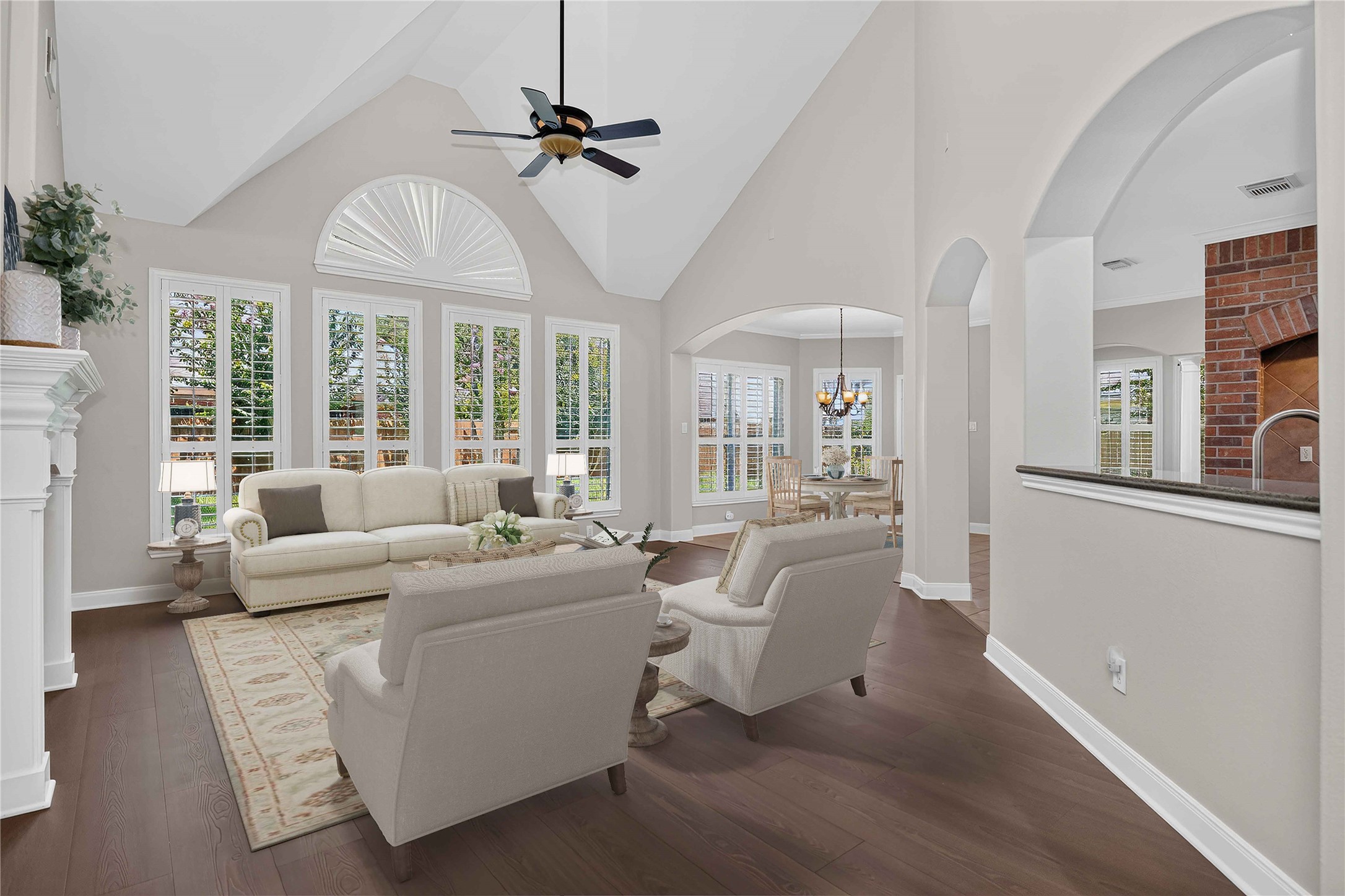 3303 Raleigh Row Missouri City, TX 77459 - Photo 13 of 50 Spacious living area with high vaulted ceilings, elegant Laminate wood flooring, and abundant natural light streaming through large windows adorned with shutters. The room seamlessly flows into a charming nook under an arched entryway.