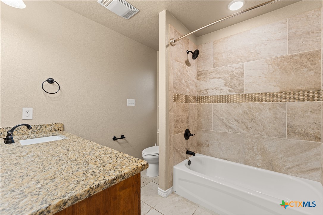 250 Old Waco Road Gatesville, TX 76528 - Photo 16 of 23 a bathroom with a granite countertop sink a toilet and bathtub