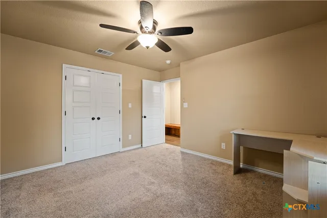 an empty room with chandelier fan and windows