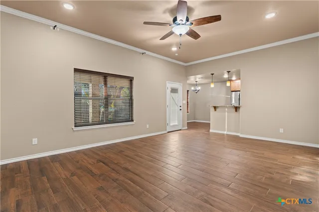 a view of an empty room with a window and wooden floor