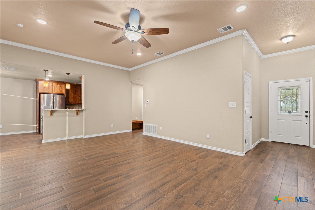 250 Old Waco Road Gatesville, TX 76528 - Photo 4 of 23 a view of an empty room with wooden floor and a ceiling fan