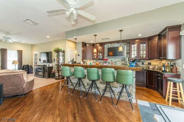 a kitchen with stainless steel appliances kitchen island granite countertop wooden floors and chairs