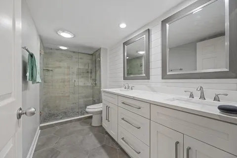a bathroom with a double vanity sink toilet and shower