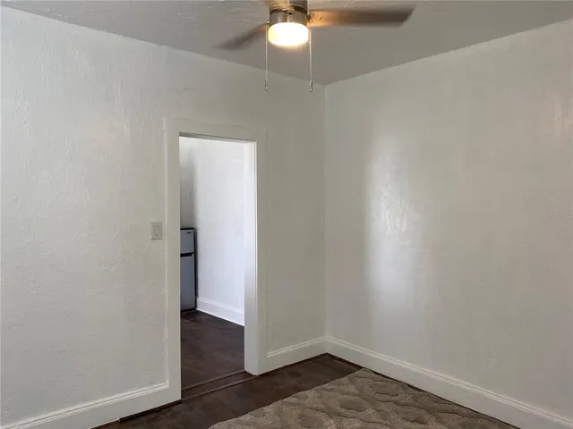 an empty room with wooden floor and fan