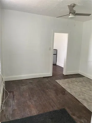 an empty room with wooden floor and fan