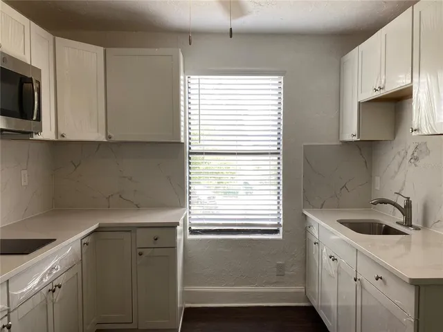 a kitchen with stainless steel appliances granite countertop a sink a microwave a window and cabinets