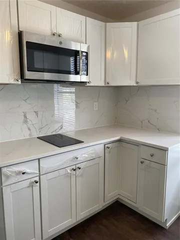 a kitchen with stainless steel appliances granite countertop white cabinets a microwave a sink and dishwasher with wooden floor