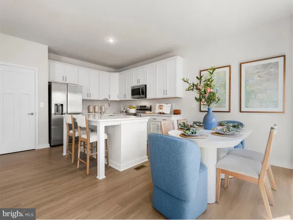 a dining room with stainless steel appliances a dining table wooden floor and a window