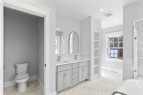 a spacious bathroom with a toilet sink and mirror